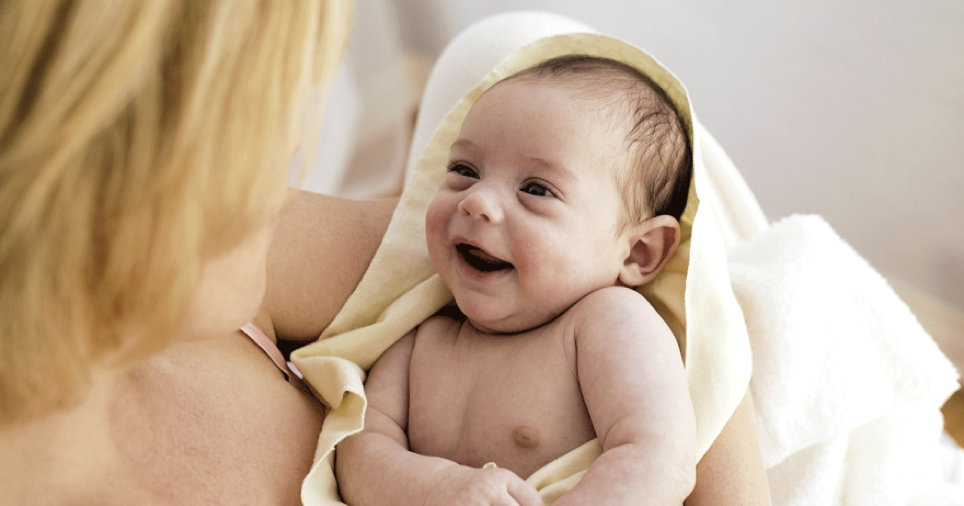 mum holding new born wrapped in a yellow blanket