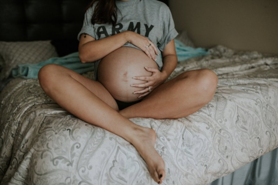 Pregnant woman holding her belly sitting on a bed