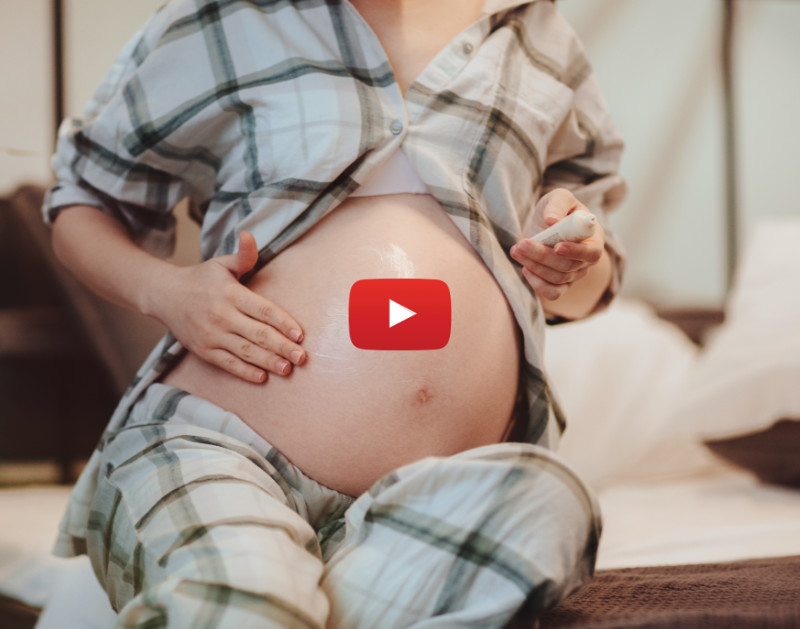 Pregnant woman rubbing cream on her belly to ease stretch marks