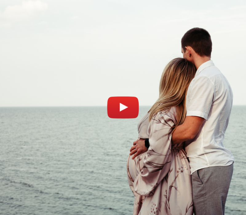 Pregnant woman with husband looking out over the ocean