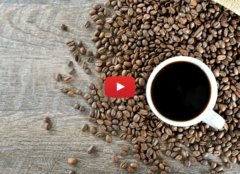 Cup of coffee sitting in a pile of coffee beans spilling out of a burlap bag