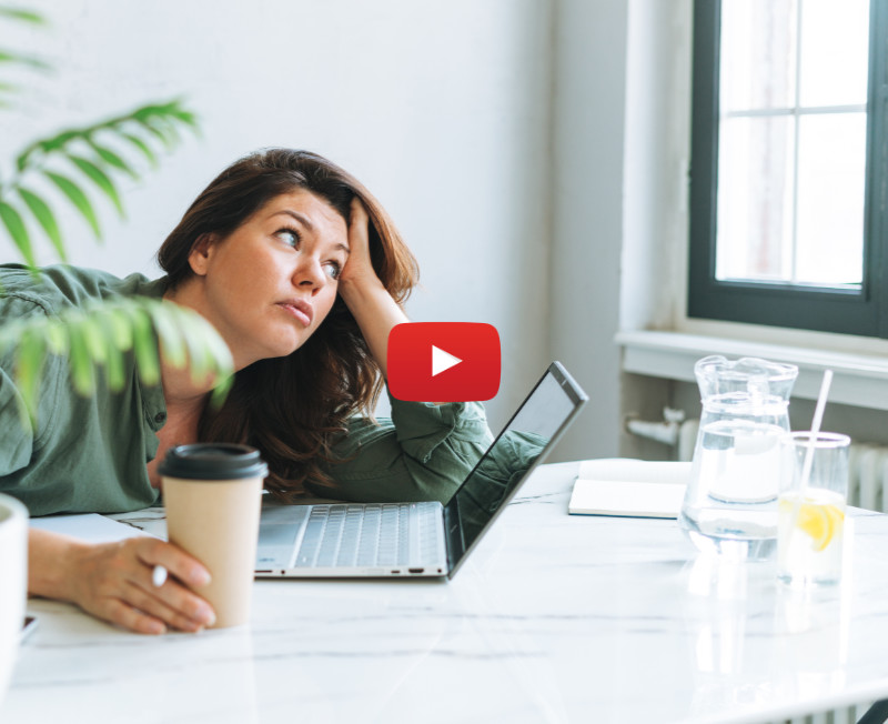 Young woman working on a laptop, drinking coffee and looking out the window